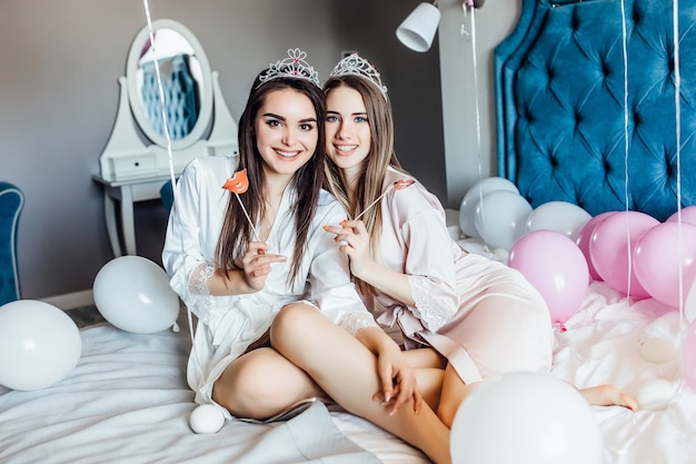 Chicas enviando un beso al aire, mirando al frente con despedida de soltera en casa con globos