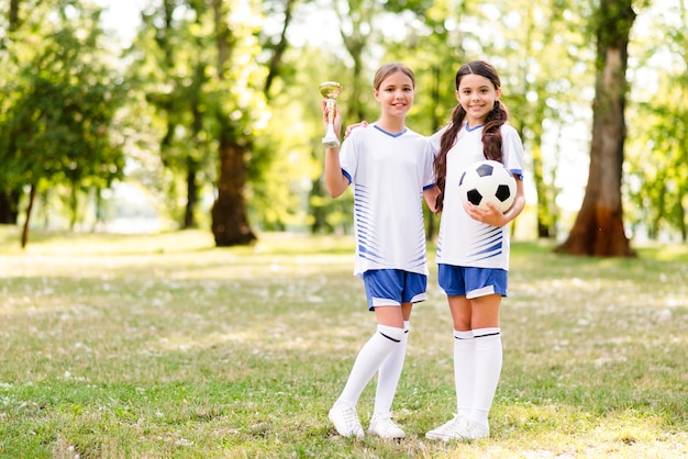 Chicas en equipos de fútbol posando con espacio de copia