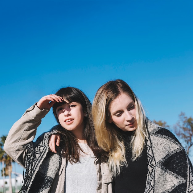 Chicas con estilo en bufanda de pie en abrazo