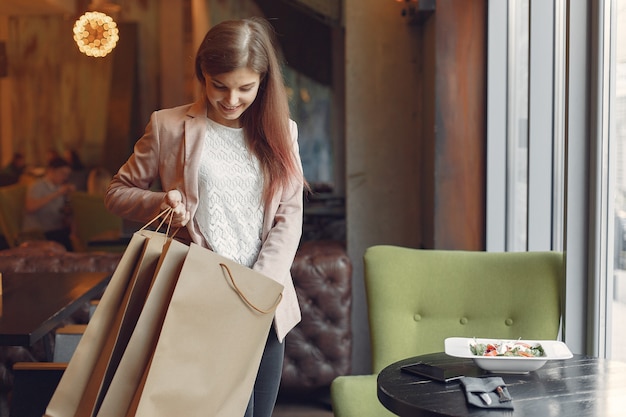 Chicas con estilo en pie en una cafetería con bolsas de compras