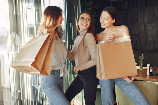 Chicas con estilo de pie en una cafetería con bolsas de compras