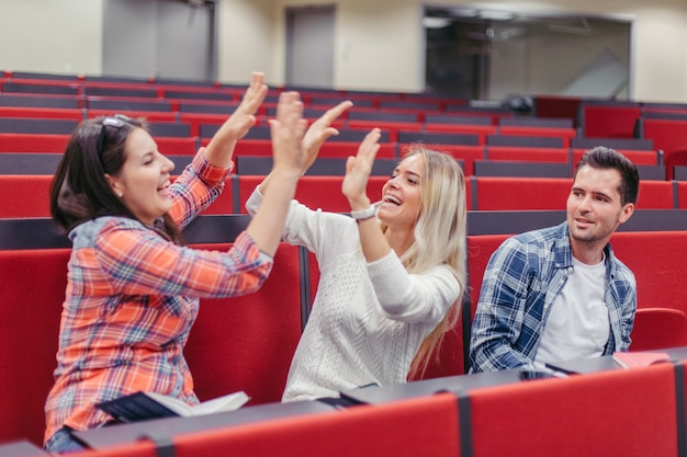 Las chicas estudiantes se dan el uno al otro cinco