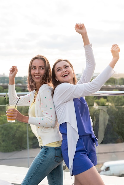 Chicas felices bailando espalda con espalda