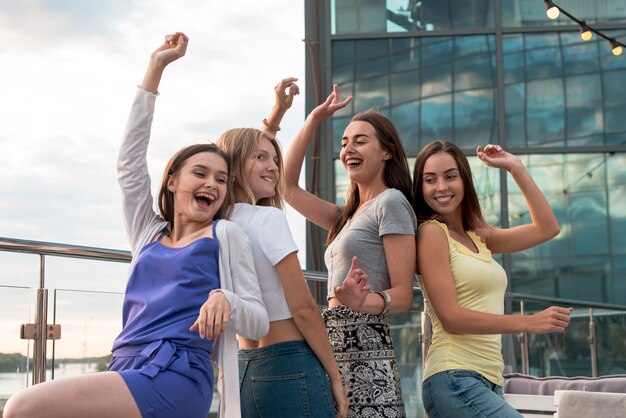 Chicas felices bailando espalda con espalda