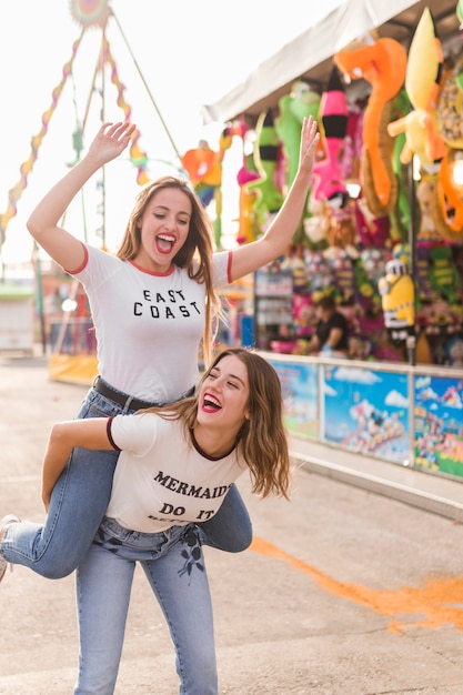 Chicas felices divirtiéndose en el parque de atracciones