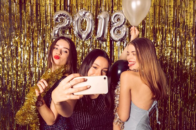 Chicas felices haciendo un selfie en celebración de año nuevo