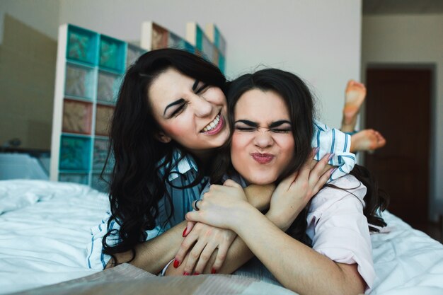 Chicas felices posando en la cama