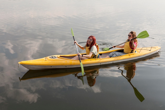 Chicas felices remando en kayak