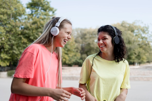 Foto gratuita chicas felices de tiro medio escuchando música