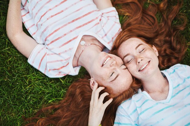 Chicas gemelas de jengibre que se preocupan unas por otras divirtiéndose en un día soleado de verano en el parque Escuchar a tus familiares es importante Concepto familiar
