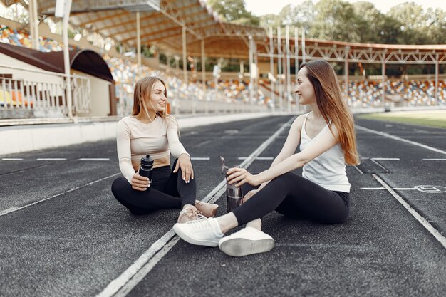 Chicas guapas en el estadio. Chicas deportivas en ropa deportiva. Personas con botella de agua.