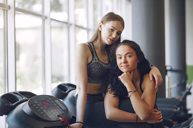 Chicas guapas en un gimnasio. Señoras deportivas en ropa deportiva. Entrenamiento de amigos