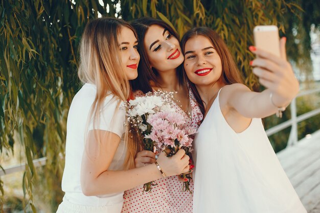 Chicas guapas en un parque de verano con un teléfono.