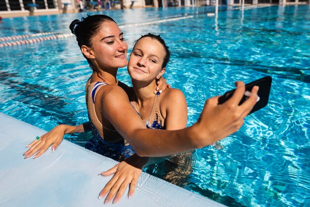 Chicas guapas tomando un selfie en la piscina