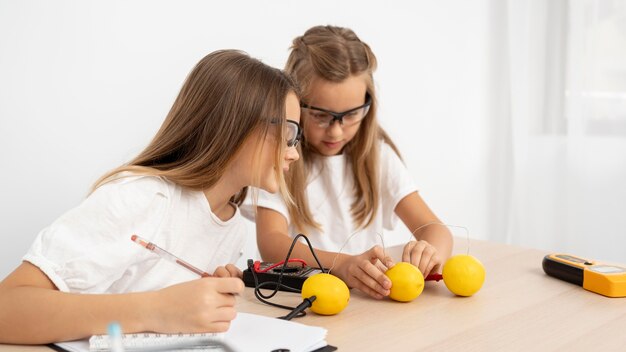 Chicas haciendo experimentos científicos con limones.