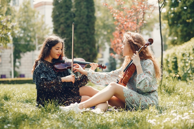 Chicas hermosas y románticas en un parque con un violín