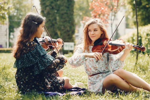 Chicas hermosas y románticas en un parque con un violín