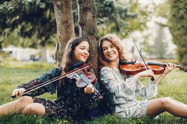 Chicas hermosas y románticas en un parque con un violín