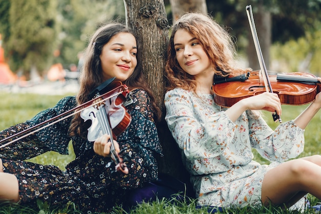 Chicas hermosas y románticas en un parque con un violín