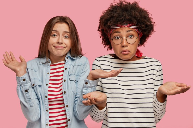 Foto gratuito chicas indecisas y desconcertadas de diferentes razas, hombros abiertos por la perplejidad, no pueden tomar decisiones sobre algo, no ven salida