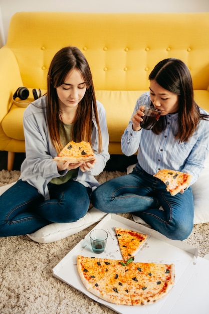 Chicas jóvenes compartiendo pizza y enfriando