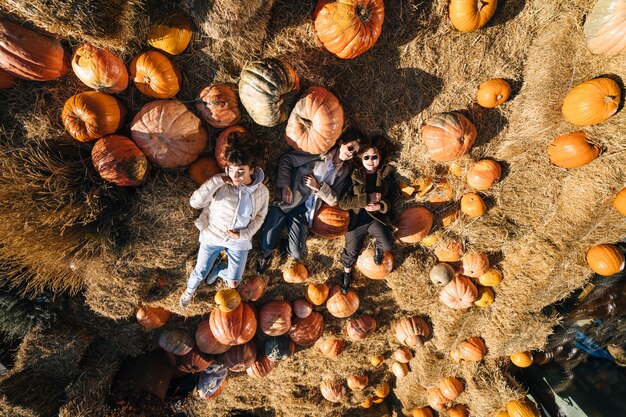 Las chicas jóvenes mienten en los pajares entre calabazas. Vista desde arriba