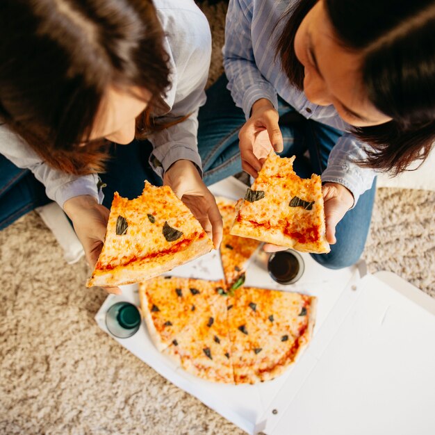 Chicas jóvenes con pizza en el piso