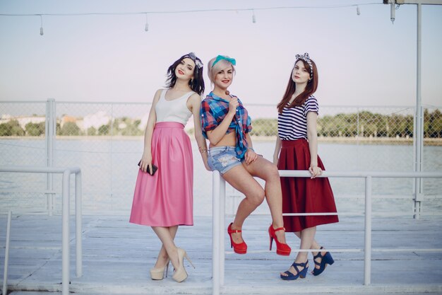 Chicas jóvenes posando en una barandilla de un puerto marítimo