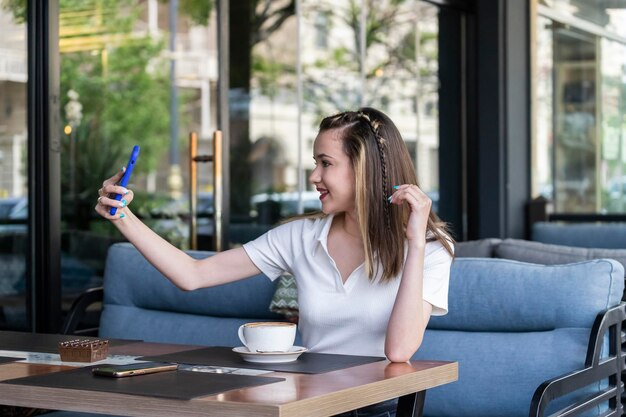 Chicas jóvenes sentadas en el restaurante y tomando selfie