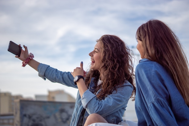 Foto gratuita chicas jóvenes tomando un selfie en un skatepark bajo la luz del sol y un cielo nublado