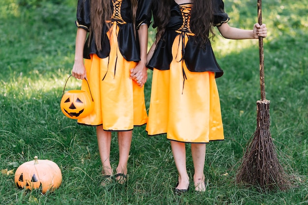 Chicas jóvenes vestidas de Halloween con calabaza y escoba en el bosque