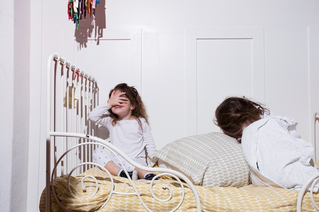 Chicas juguetonas en la cama acogedora