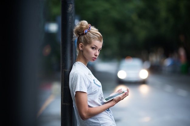 Chicas lindas con tableta en una parada de autobús