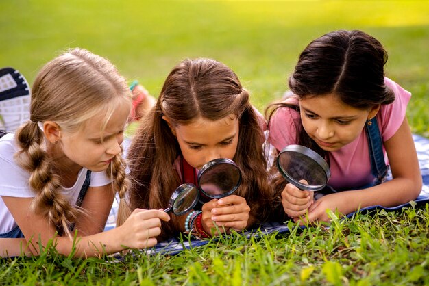 Chicas mirando la hierba a través de la lupa