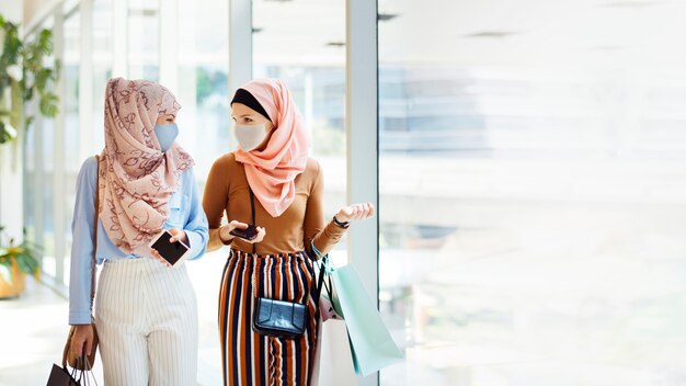 Chicas musulmanas con máscaras faciales en el centro comercial