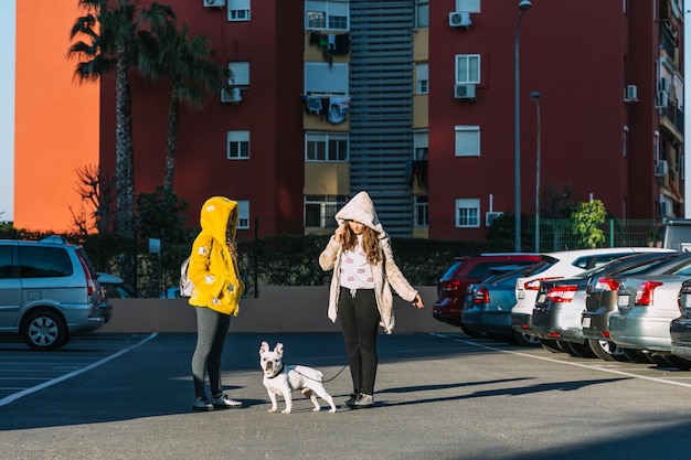 Chicas con perro andando en parking