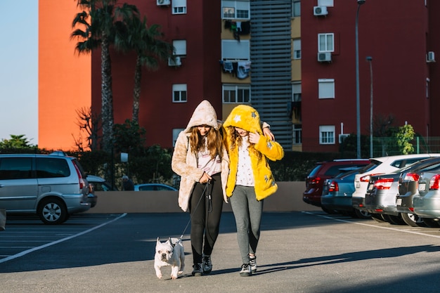 Chicas con perro andando en parking