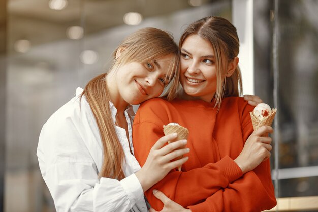 Chicas de pie en una ciudad de verano con helado