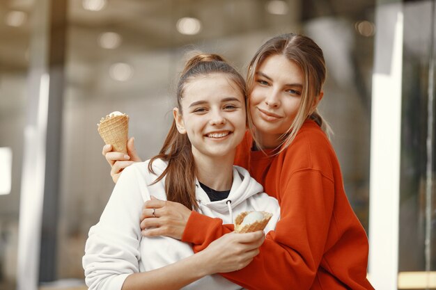 Chicas de pie en una ciudad de verano con helado