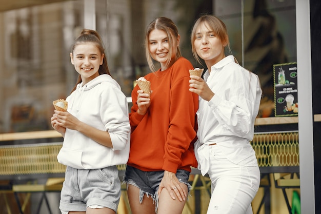 Chicas de pie en una ciudad de verano con helado