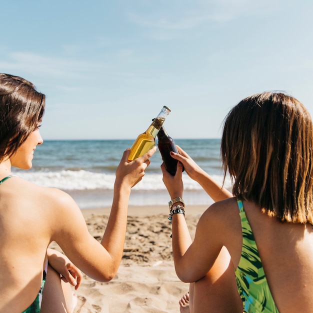 Chicas en la playa brindando con cerveza