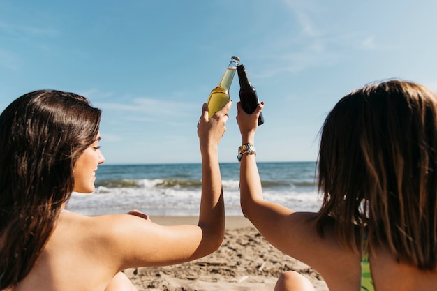 Chicas en la playa brindando con cerveza