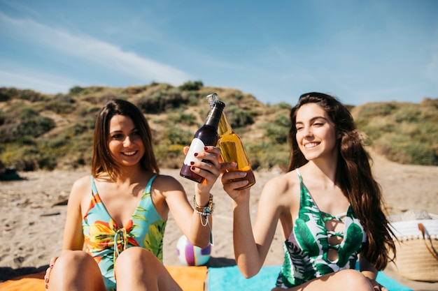 Chicas en la playa brindando con cerveza