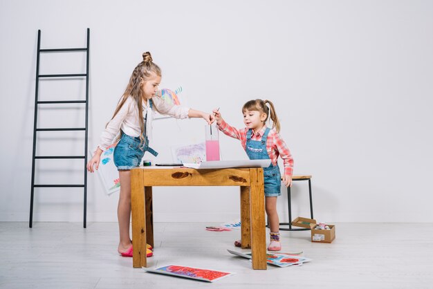 Chicas poniendo pinceles en un vaso de agua