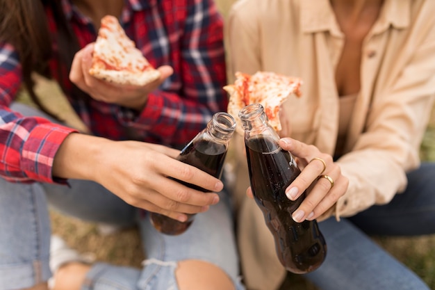 Chicas de primer plano con pizza y refrescos