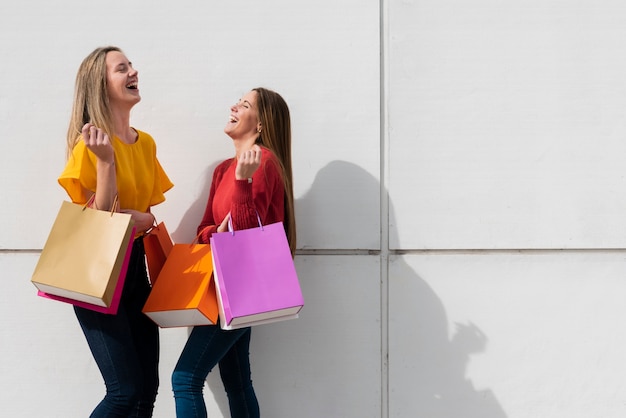 Chicas riendo con bolsas de compras