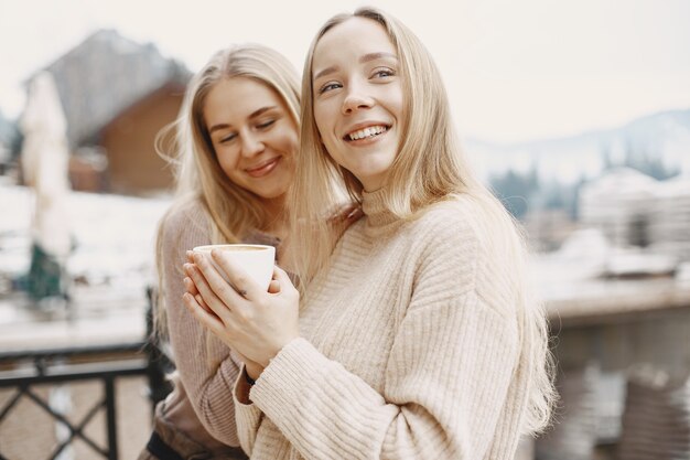 Chicas con ropa ligera. Café de invierno en el balcón. Mujeres felices juntas.