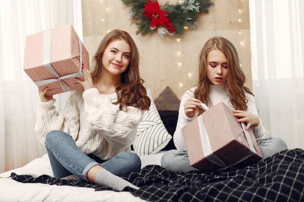 Chicas sentadas en la cama. Mujeres con cajas de regalo. Amigos preparándose para la Navidad.