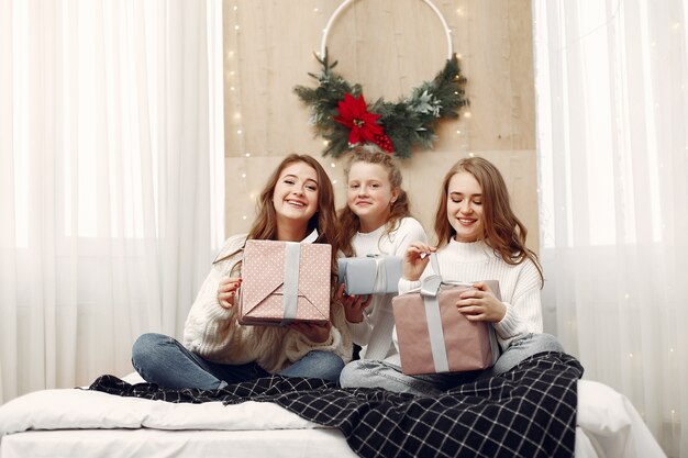 Chicas sentadas en la cama. Mujeres con cajas de regalo. Amigos preparándose para la Navidad.