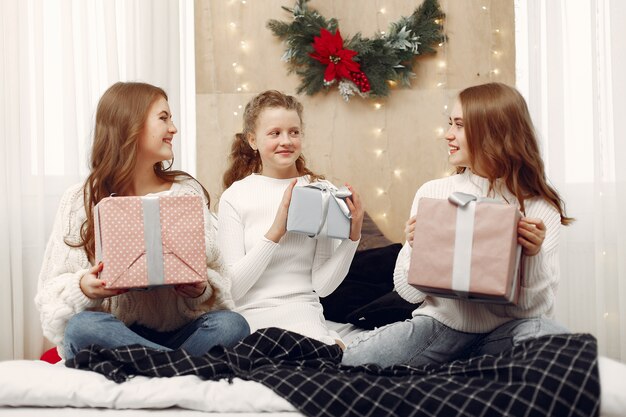 Chicas sentadas en la cama. Mujeres con cajas de regalo. Amigos preparándose para la Navidad.